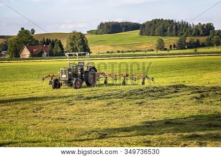 The Tractor And Hay Tedder Prepare Hay Harvest For Cultivation. Agriculture And Agronomy Concept. Se