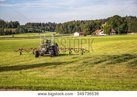 The Tractor And Hay Tedder Prepare Hay Harvest For Cultivation. Agriculture And Agronomy Concept. Se