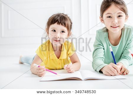 Happy Two Little Girl Drawing And Do Homework On The Flloor