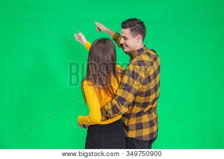 Amazed Young People Looking And Pointing Away At Something Really Increadible On Green Background.