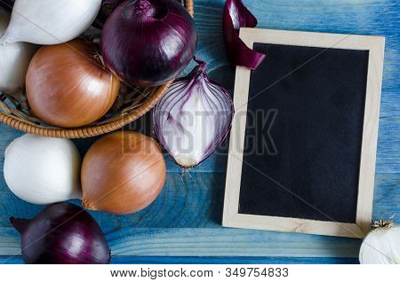 Red, White, And Beige Onions On A Blue Background Dark-colored Placard For Text