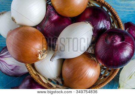 Red, White And Yellow Onions In A Wicker Basket Close-up View From Above