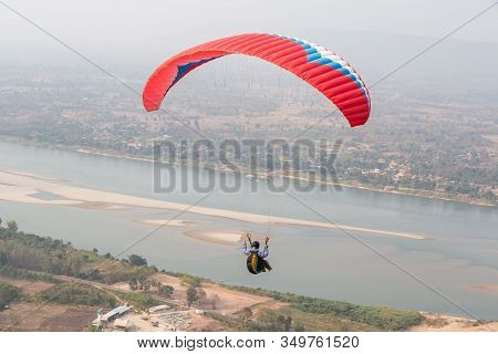 Paragliding In The Sky. Paraglider  Flying Over Landscape From Beautiful View Mekong River At Wat Ph