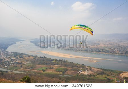 Paragliding In The Sky. Paraglider  Flying Over Landscape From Beautiful View Mekong River At Wat Ph