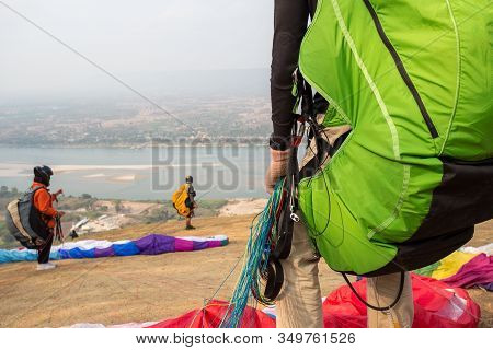Paraglider On The Ground. Paragliders With Full Flight Equipment Look On Soaring Another Paragliders