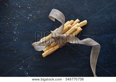 Closeup Of Grissini Breadsticks Tied Together With A Ribbon On Dark Background, Breadsticks Top View