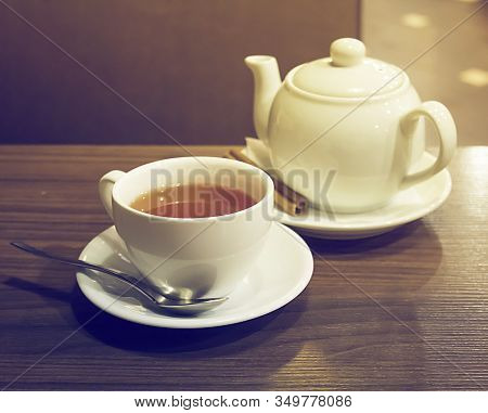 Porcelain Teapot, Teacup, Spoon And Canella On Wooden Table.
