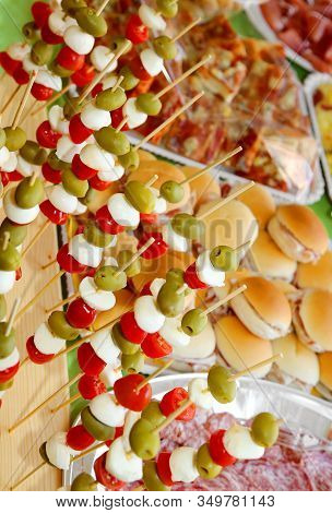 Many Skewers With Olives, Mozzarella Cheese Of Bufala, Mortadella And Red Tomatoes And A Lot Of Food
