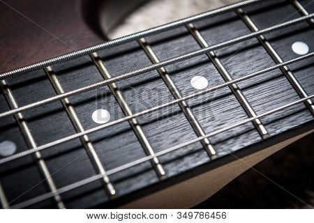 Bass Guitar With Four Strings Closeup. Detail Of Popular Rock Musical Instrument. Close View Of Brow