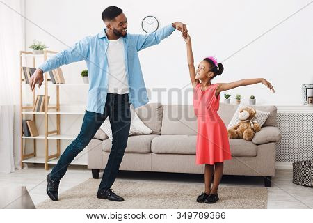 Fatherhood Concept. Cute Girl Dancing With Father, Feeling Like Princess At Home