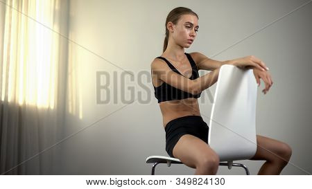 Skinny Girl Sitting On Chair, Exhausted By Malnourishment, Anorexia, Depression