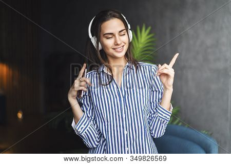 Millennial Woman Listening To Music Wearing Wireless Headphones. Girl Dancing And Having Fun While E