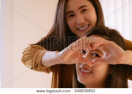 Happy Woman Day. Two Beautiful  Woman Friends Holding Heart Shaped Hands. Healthy Eyes And Vision.