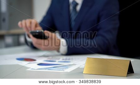 Busy Man In Suit Using Phone, Documents On Table, Blank Nameplate Template