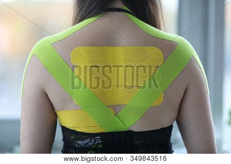 Female Wearing Kinesio Tapes At Her Back And Shoulders At Doctor Office Closeup