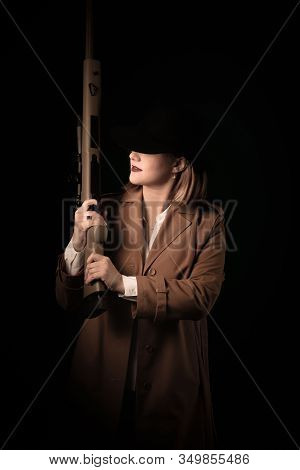 A Woman In A Brown Cloak And A Black Hat With Airguns In Her Hands Looks Into The Sight. Gangster St