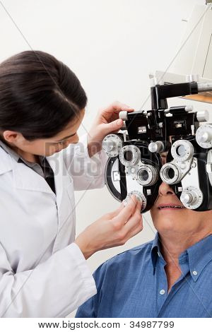 Kvindelige optometrist justering paneler af phoropter under øjet helbredsundersøgelse