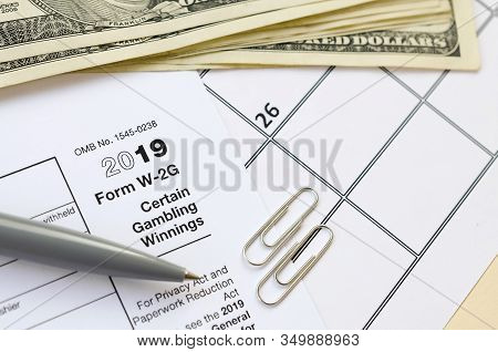 Irs Form W-2g Certain Gambling Winning Blank Lies With Pen And Many Hundred Dollar Bills On Calendar