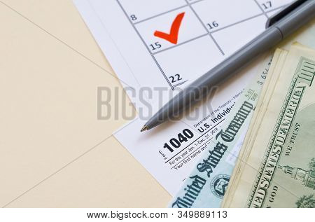 1040 Individual Income Tax Return Form With Refund Check And Hundred Dollar Bills On Calendar With M