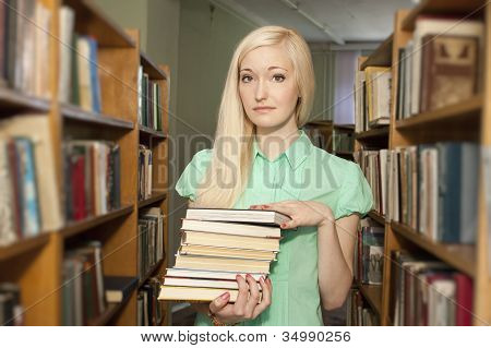 Mujer joven con libros en la biblioteca