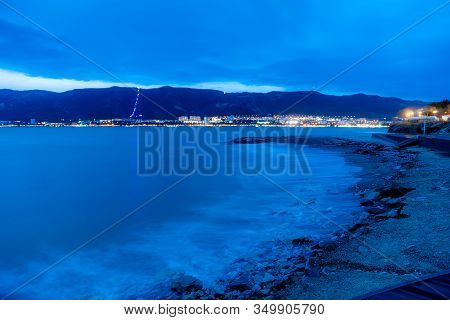 Gelendzhik Beach In The Evening In A Storm. The Waves At High Speed Turn Into A Blue Fog. Pebble Bea