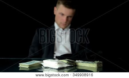 Contrabandist Looking At Coke, Money And Balaclava On Table, Drug Dealer, Trade
