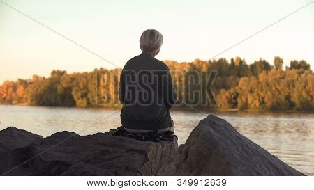 Lonely Old Woman Sitting Near Lake And Throwing Stones Solitude, Back View