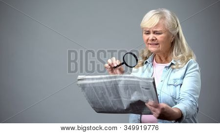 Elderly Lady Trying To Read Newspaper With Magnifying Glass, Poor Vision Problem