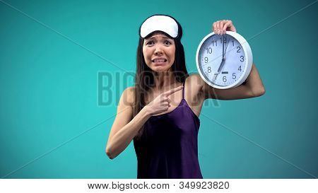 Frustrated Girl Pointing At 7 Am On Clock Face, Overslept And Getting Late