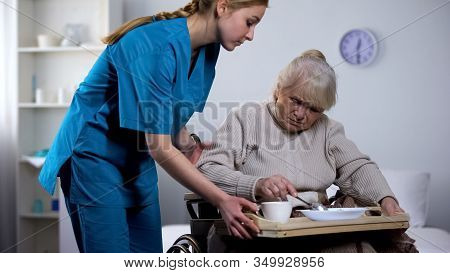 Nurse Serving Unappetizing Diet Dinner To Old Handicapped Woman, Taking Care