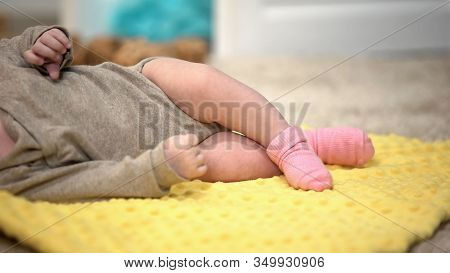 Charming Baby Girl Lying On Yellow Blanket, Thigh Joints Dysplasia Prevention