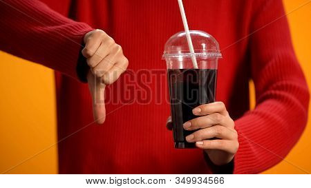 Woman With Soft Drink Glass Showing Thumbs Down, Sweet Beverage Disapproval