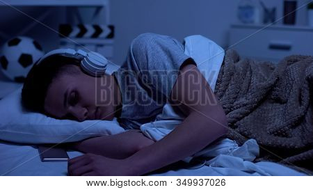Male Teenage Boy Fallen Asleep In Headphones, Overworked Student Relaxing
