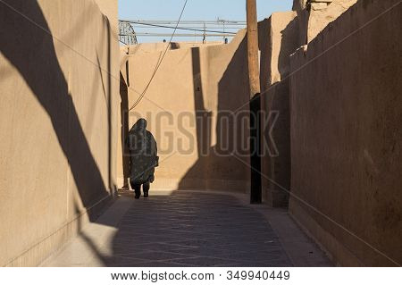 Shape Of A Woman Walking In The Streets Of Yazd, Iran, Passing Near A Traditional Clay Walls Of The 