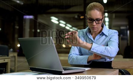 Tired Woman Checking Time On Watch, Working Overhours In Office To Meet Deadline