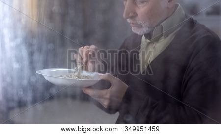 Senior Male Looking At Tasteless Porridge, Low Social Allowance, Lack Of Money