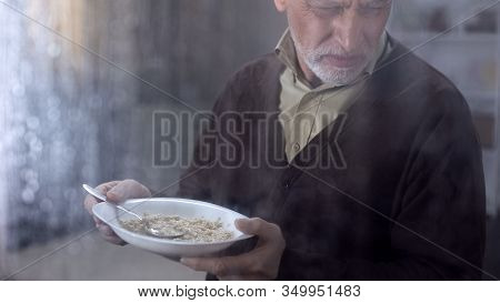Retired Man Holding Plate With Disgusting Tasteless Oatmeal, Lack Of Money