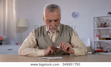 Senior Male Trying To Collect Puzzle, Memory Problems, Cognitive Impairment