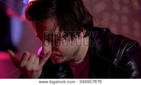Depressed Young Man Snorting Coke Powder In Night Club, Drug Abuse Problem