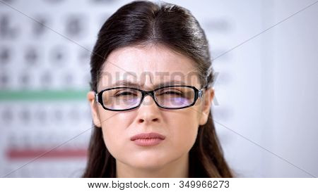 Female Patient In Inappropriate Glasses Squeezing Eyes, Suffering Blurred Vision
