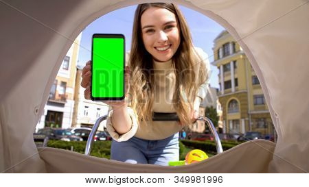 Smiling Mom Showing Green Screen Smartphone To Baby In Carriage, Lullaby App