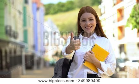 Happy Female High-schooler With Rucksack And Books Gesturing Thumbs-up, Student