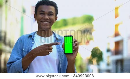 Happy Male Teenager Pointing Finger Into Green Screen Smartphone, Touristic App