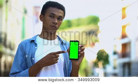 Mixed-race Teenager Pointing At Green Screen Smartphone, Games And Messengers