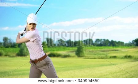Slim Woman With Golf Club Performing Swing Hitting Ball, Luxury Hobby, Sport