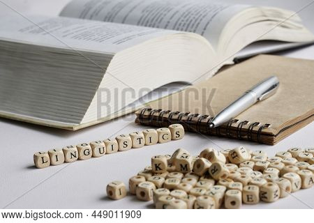 Word Linguistics Next To Notebook, Pen, Open Book And Many Letters. Concept Of The Study Of The Huma