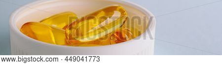Yellow Softgels Or Capsules Are In White Bottle Cap. Fish Oil. Light Blue Surface. Vitamins And Heal