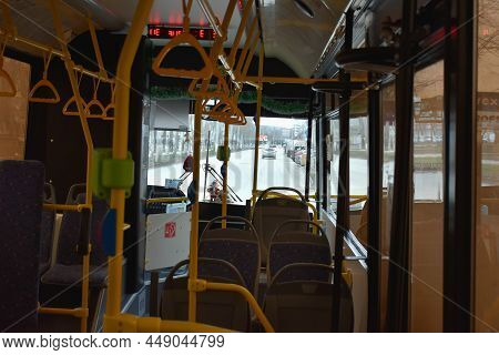 The Interior Of A City Shuttle Bus Traveling Down The Street Without Passengers. Seats, Yellow Handr