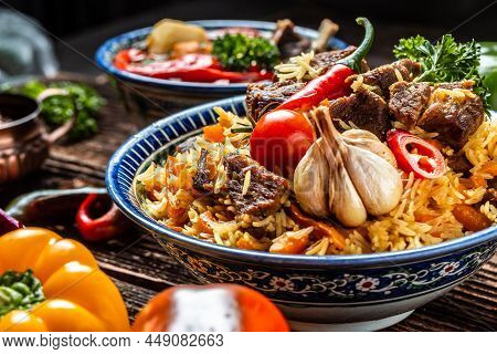 Traditional Uzbek Meal Called Pilaf. Rice With Meat On Plate With Oriental Ornament On A Dark Wooden