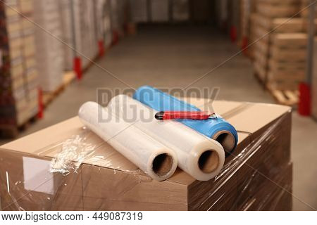 Rolls Of Different Stretch Wraps And Utility Knife On Boxes In Warehouse